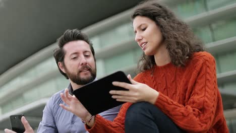 Smiling-man-and-woman-using-tablet-pc-outdoor